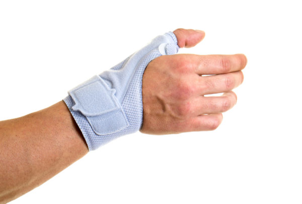 Close Up of Man Wearing Modern Supportive Orthopedic Brace on Wrist  Hand and Thumb  Secured by Velcro Strap  in Studio with White Background and Copy Space.